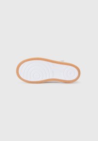 Hvite sneakersåler med sirkulære og lineære mønstre, med en gummirand og teksturerte spor for grep.