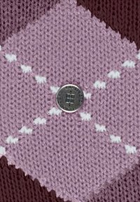 Tessuto a maglia rosa con un motivo a rombi e dettagli bianchi, bottone centrale argento con un design circolare, su uno sfondo scuro.