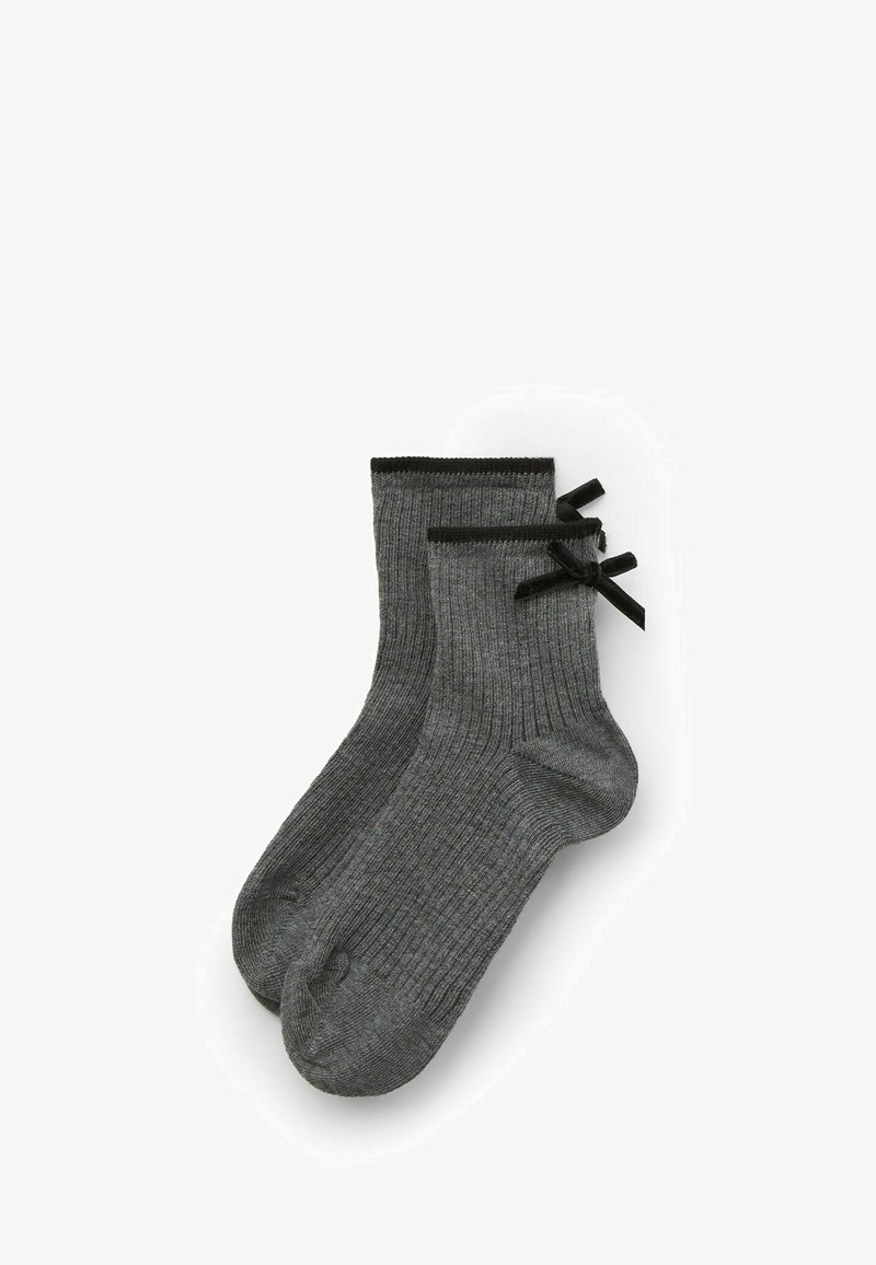 Calze grigie a costine con una trama morbida, caratterizzate da fiocchi neri decorativi nella parte superiore. Di lunghezza alla caviglia, progettate per comfort e stile.
