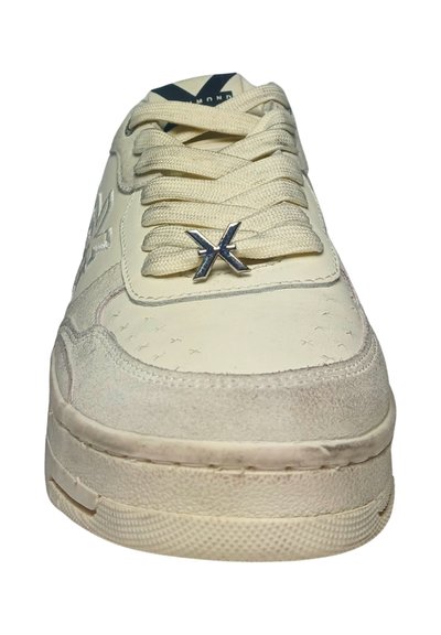 Sneaker color crema con tomaia testurizzata, punta rotonda e lacci piatti. Presenta un'accattivante accentatura in logo argentato e una suola in gomma.