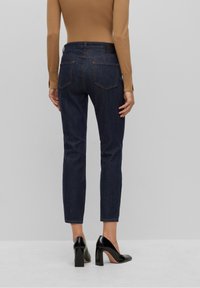 Mörka denimjeans med slim fit, har två bakfickor, kontrasterande sömmar och en märkesläderlapp vid midjan.