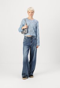 Light blue lace long-sleeve top, high-waisted wide-leg denim jeans, gray crossbody bag, black sneakers. Textured patterns evident in fabric.