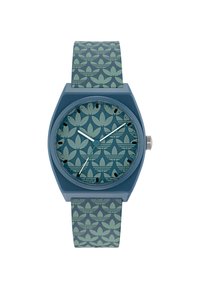 Montre bleue avec un boîtier hexagonal, cadran à motifs comportant des formes vert clair, et bracelet texturé assorti. Couronne en argent sur le côté.