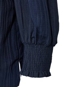Marineblauwe blouse van textuur met verticale strepen, geplooide pofmouwen en smockmanchetten met een gerimpelde zoom. Lichtgewicht stof.