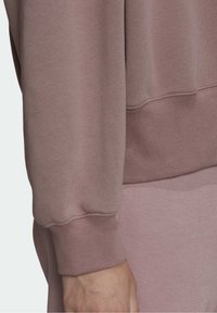 Rosa sweatshirt i bomullsblandning med ribbad nederkant och mudd vid ärmslut, med en mjuk textur. Designen har en avslappnad passform och minimal detaljering.