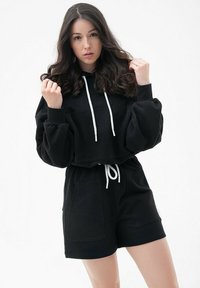Czarna, krótka bluza z kapturem i sznurkiem, zdobiona białymi akcentami, w połączeniu z czarnymi szortami z bocznymi kieszeniami i elastycznym paskiem w talii.