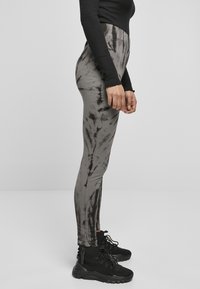 Leggings a vita alta con un motivo tie-dye grigio e nero, realizzati in tessuto elasticizzato, abbinati a sneakers nere con texture.