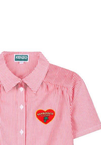 Chemise rayée rouge et blanche avec un col, ornée d'un patch en forme de cœur brodé portant l'inscription "SUNKISSED by KENZO" et une fermeture à boutons.