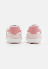 Bílé a růžové dětské tenisky z hladké kůže, s polstrovanými patkami a gumovou podrážkou. Zapínání na suchý zip pro snadné obouvání.