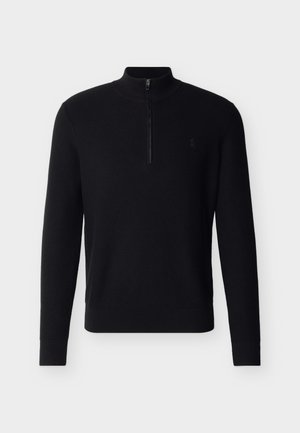 Μαύρο πλεκτό πουλόβερ με μακριά μανίκια, υφή, φερμουάρ στο επάνω μέρος και ριμπ τελειώματα στα μανίκια και στη μέση, απεικονίζεται σε απλό ανοιχτό γκρι φόντο.