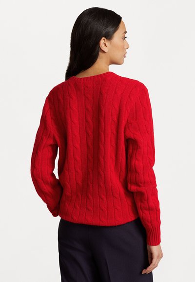 Jersey rojo de punto trenzado con mangas largas, escote redondeado y puños y dobladillo de canalé. La textura es gruesa y tejida.