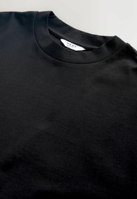 Czarna bawełniana koszulka z klasycznym dekoltem. Gładka tekstura z metką "NEXT" umieszczoną wewnątrz dekoltu.