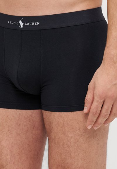 Boxer-briefs en coton noir avec une ceinture élastique robuste sur laquelle est inscrit "RALPH LAUREN" en blanc. Texture lisse et design ajusté.