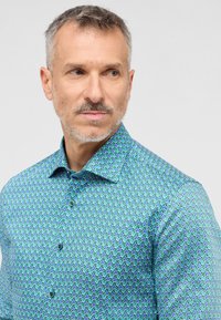 Blauwe en groene geblokte dress shirt met een button-down kraag, met een klein geometrisch ontwerp en een soepele textuur. Twee knopen zichtbaar.