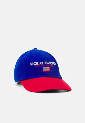 Casquette Polo Sport Ralph Lauren bleue et rouge avec broderie du drapeau américain sur le devant, présentée sur fond blanc.
