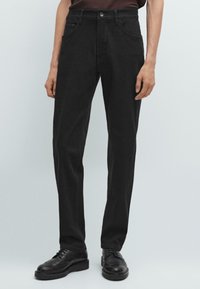 Zwarte denim pantalon met een recht gesneden pijp, vijf zakken, knoopsluiting en subtiele stikdetails. Gladde textuur, standaard tailleband.