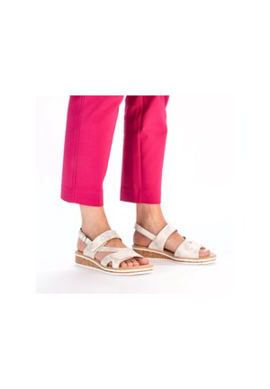Light gray suede sandals with crisscross straps, an open toe design, and a slight wedge cork sole, paired with pink cropped pants.