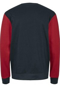 Tröja med marinblå kropp och röda ärmar. Ribbad mudd och fåll. Tillverkad av mjukt tyg med en strukturerad yta. Enkel, sportig design.