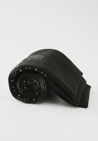 Schwarze, gerollte Socken mit einer glatten Textur, die ein geometrisches graues Muster am Rand und subtile weiße Akzente aufweisen.