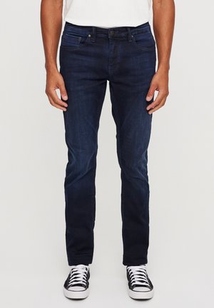 Dunkelblaue Denim-Jeans mit einem Fünf-Taschen-Design, gerader Schnitt, leichtem Stretch und abgerundet mit Details in Schwarz und Weiß bei den Sneakers.