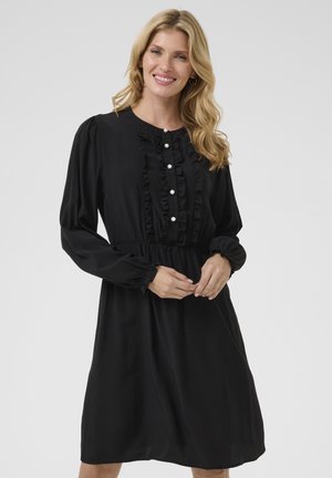 Schwarzes Kleid aus leichtem Stoff, mit einem gerafften Vorderteil, Perlenknopfdetails, langen Ärmeln und einem elastischen Bund.