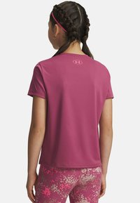Short-sleeve athletic top in pink fabric with a smooth texture and a logo on the back. Paired with patterned pink leggings.