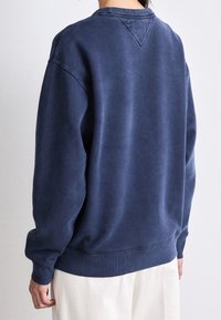 Laivansininen collegepaita, jossa on rento malli. Varustettu ribbauskauluksilla ja -hihoilla, pyöreällä kaula-aukolla ja V-muotoisella takadetaililla. Pehmeä pinta.