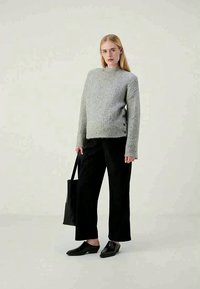 Ανοιχτό γκρι πλεκτό πουλόβερ με στρογγυλή λαιμόκοψη, υφή και ριμπ ρεβέρ. Συνδυασμένο με μαύρο φαρδύ παντελόνι και μαύρες παπούτσια, κρατώντας μια τσάντα tote.