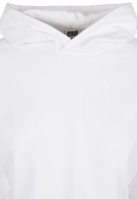 Bela bombažna jopa z velikim kapuco, rebrastimi manšetami in sproščenim krojem. Notranjost ima etiketo z napisom "URBAN CLASSICS." Brezšivna zasnova.