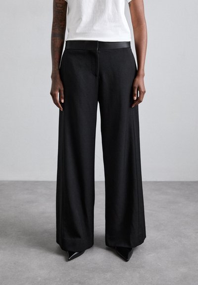 Pantalons noirs à jambes larges en matériau léger, dotés d'une taille lisse et d'une finition soignée et ajustée.