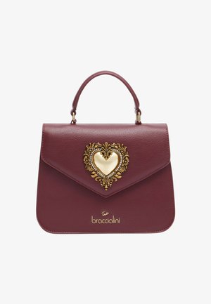 Borsa in pelle color bordeaux con ornamento a forma di cuore in oro decorato con gioielli. Presenta un design strutturato e un manico superiore.
