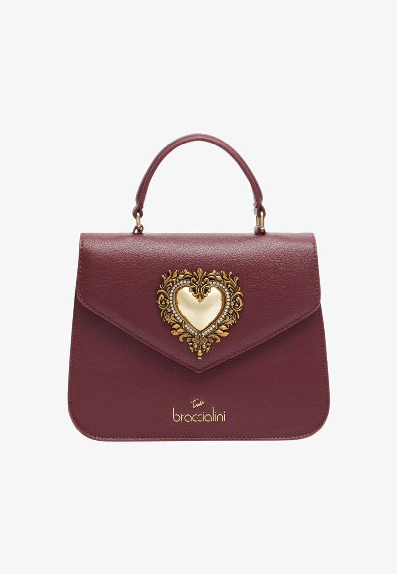 Borsa in pelle color bordeaux con ornamento a forma di cuore in oro decorato con gioielli. Presenta un design strutturato e un manico superiore.