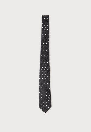 Corbata negra con pequeños lunares blancos uniformemente espaciados sobre un fondo claro liso.