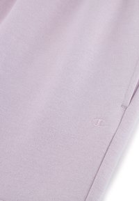Lichtlavender joggers van zachte stof met een subtiele textuur. Kenmerken omvatten een logodetail, een elastische tailleband en een zijzak.