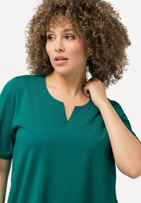 Top verde acqua con scollo a V e maniche corte, caratterizzato da una texture sottile. Presenta una cucitura attorno al collo. Adatto per un abbigliamento casual.