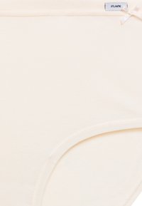 Beżowa bawełniana bielizna o gładkiej fakturze, z małą kokardką jako ozdobą oraz metką z napisem "ATLANTIC" umieszczoną blisko pasa.