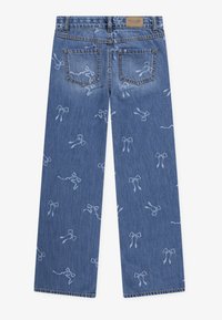 Plave traperice s laganim uzorkom mašne, dva stražnja džepa, ravne nogavice i smeđa etiketa branda na pojasu.