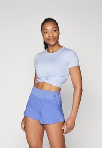 Crop top corto azzurro chiaro con design anteriore attorcigliato abbinato a pantaloni shorts larghi in lavanda a vita alta. Tessuto dalla texture morbida.