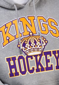 Grauer Hoodie mit "KINGS" in Lila und "HOCKEY" in Gelb. Über dem Text befindet sich ein Kronen-Graphic, mit Kordeln in passender Farbe.
