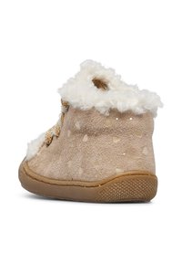 Stivaletto in suede beige con collo bianco peloso, motivo a pois e lacci decorativi dorati. Suola in gomma flessibile con grip testurizzato.