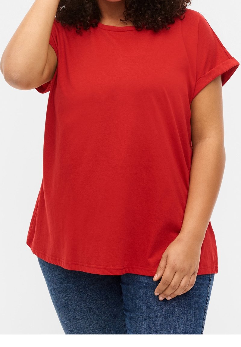T-shirt rouge à manches courtes avec un col rond. Fabriqué en tissu doux, il présente une coupe décontractée et des manches retroussées. Associé à un jean bleu.