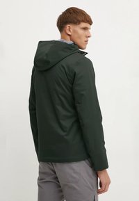Jachetă impermeabilă de culoare verde închis, cu glugă, având o textură netedă și un design ajustat. Include un guler subtil și nu are elemente de fixare vizibile.