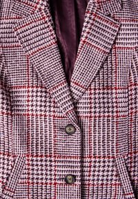 Gevlochten geruite blazer in paarse, zwarte en rode tinten. Heeft notch-revers, twee knopen, zakflappen en een gladde bordeauxrode voering.