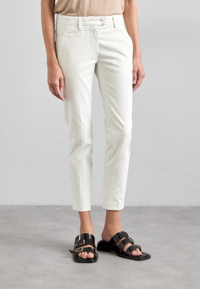 Pantaloni albi, cu croială slim-fit, cu o textură netedă și un design bine croit. Asortați cu sandale negre cu cataramă. Fără modele sau accente vizibile.