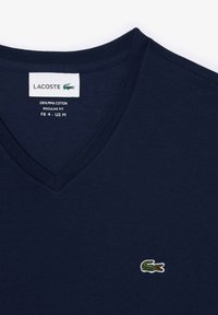 Granatowy t-shirt w serek wykonany w 100% z bawełny pima, z małym haftowanym logo krokodyla na lewej piersi. Klasyczny krój.