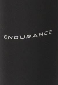 Svart sporttyg med "ENDURANCE" i metallisk silvertext, med en ren, modern design och slät textur.