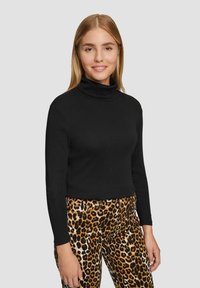 Zwarte turtleneck trui met lange mouwen, gecombineerd met geklede broek met luipaardprint, met een aansluitend ontwerp en een zachte textuur.