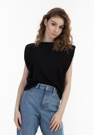Zwart mouwloos topje met een hoge halslijn en gestructureerd schouderontwerp, gecombineerd met lichtblauwe high-waisted jeans. Soepele stoftextuur.