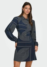 Marine jurk met lange mouwen, knoopsluiting aan de voorkant en lineaire witte patronen met krommingen en geometrische vormen. Gladde stoftextuur.