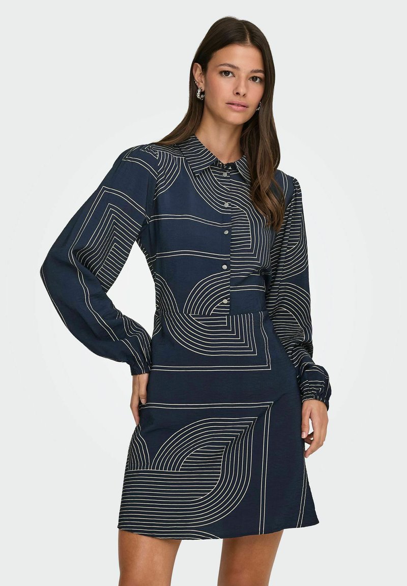 Marine jurk met lange mouwen, knoopsluiting aan de voorkant en lineaire witte patronen met krommingen en geometrische vormen. Gladde stoftextuur.